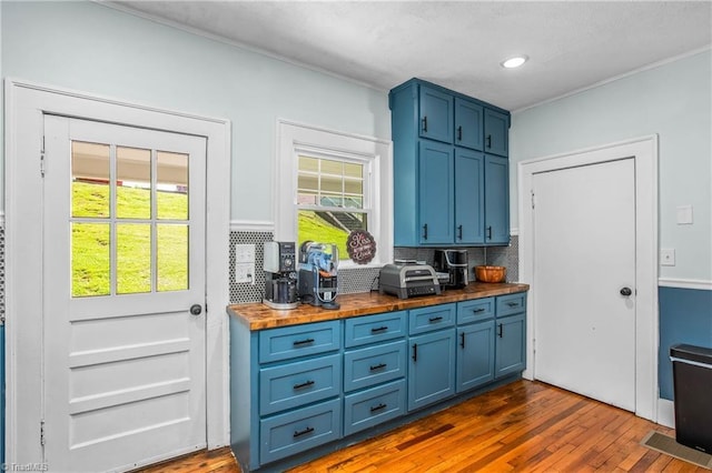 bar area featuring tasteful backsplash, dark wood-style flooring, healthy amount of natural light, ornamental molding, and recessed lighting