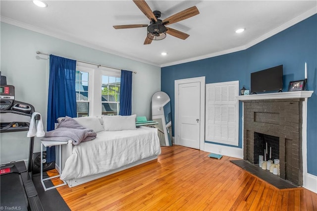 bedroom with hardwood / wood-style floors, ornamental molding, a fireplace, recessed lighting, and a ceiling fan