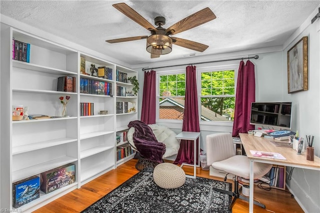 living area featuring a textured ceiling, wood finished floors, a ceiling fan, and an office area
