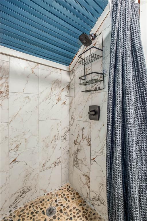 full bath featuring vaulted ceiling and tiled shower