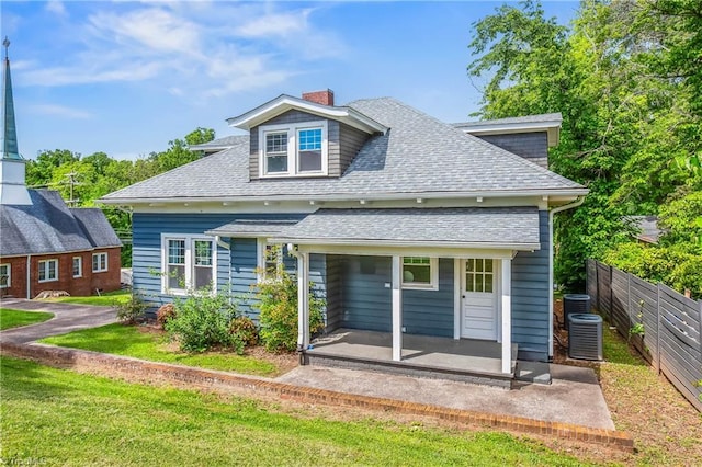 rear view of property featuring a shingled roof, a chimney, central air condition unit, and a patio