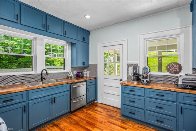 kitchen with wood counters, a sink, stainless steel dishwasher, blue cabinets, and recessed lighting