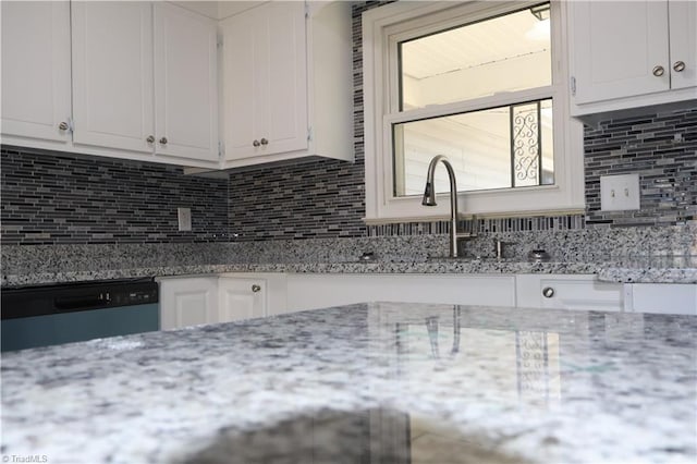 kitchen with white cabinets, dishwasher, light stone countertops, and tasteful backsplash