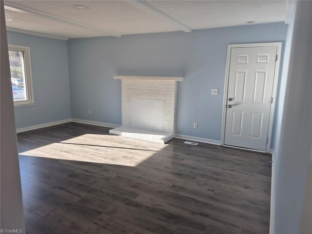 unfurnished living room with dark hardwood / wood-style floors, a textured ceiling, and a brick fireplace