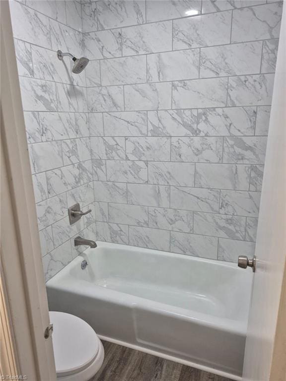 bathroom featuring hardwood / wood-style flooring, tiled shower / bath combo, and toilet