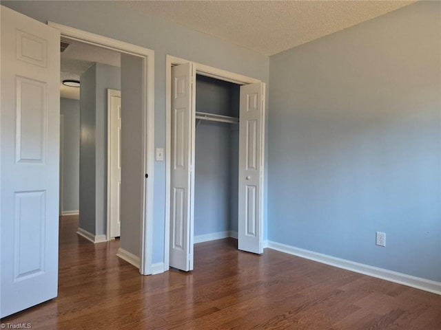 unfurnished bedroom featuring a textured ceiling, dark wood-type flooring, and a closet