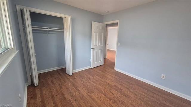 unfurnished bedroom featuring dark wood-type flooring and a closet