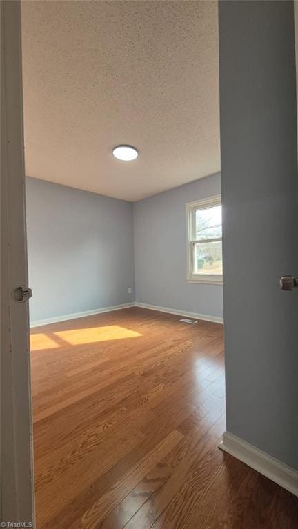 unfurnished room with hardwood / wood-style floors and a textured ceiling