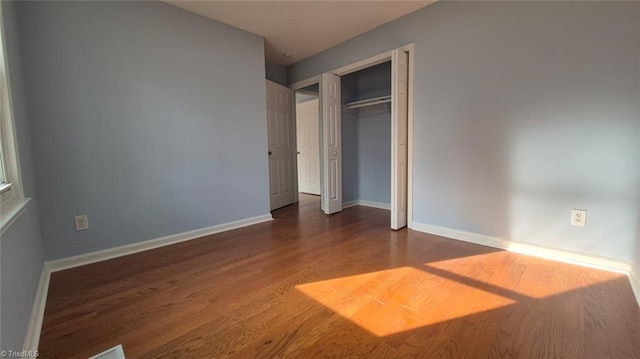 unfurnished bedroom with dark hardwood / wood-style flooring and a closet