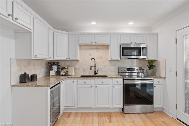 kitchen featuring light wood-type flooring, beverage cooler, sink, stainless steel appliances, and white cabinetry