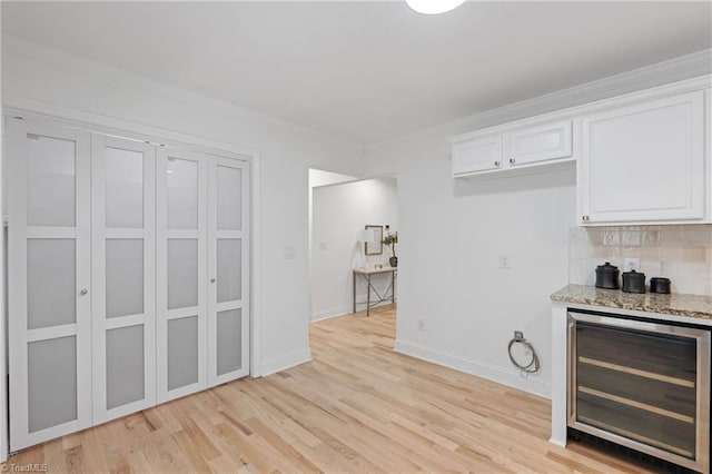 kitchen featuring beverage cooler, light hardwood / wood-style flooring, backsplash, ornamental molding, and white cabinetry