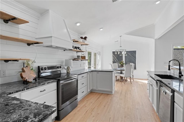 kitchen featuring stainless steel appliances, sink, light hardwood / wood-style floors, hanging light fixtures, and white cabinetry