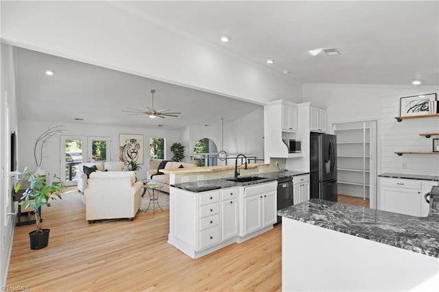 kitchen with light wood-type flooring, vaulted ceiling, sink, white cabinets, and black appliances