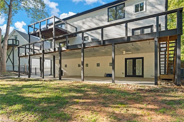 rear view of house with french doors, a patio, a yard, and a balcony