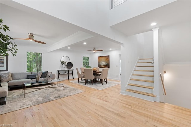 living room with ornate columns, light wood-type flooring, and ceiling fan