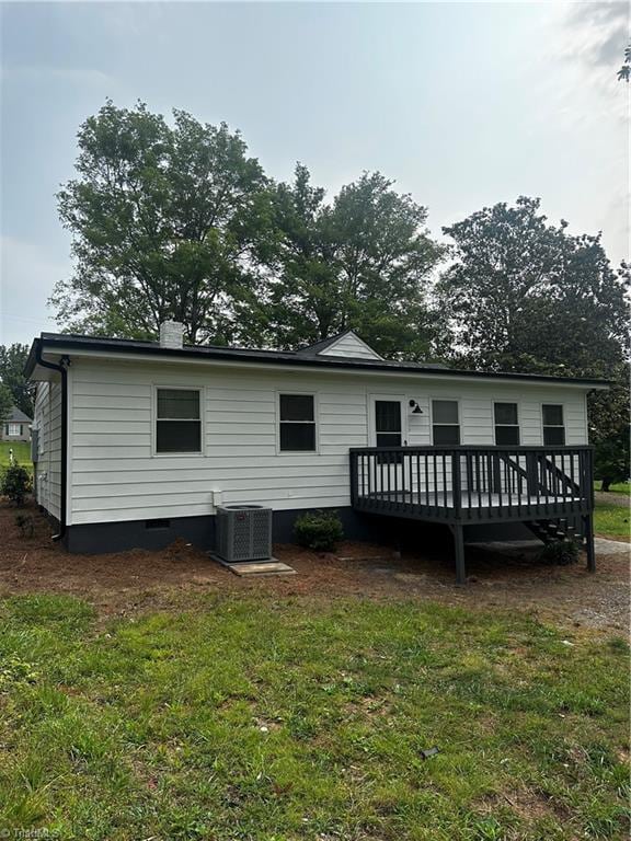 rear view of property with cooling unit, a deck, and a yard