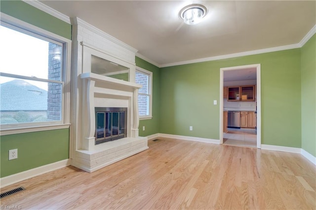 unfurnished living room with crown molding, a fireplace, a healthy amount of sunlight, and light hardwood / wood-style flooring