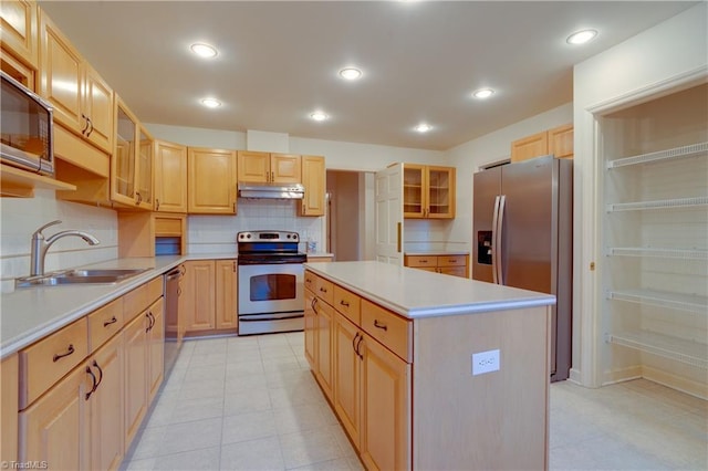 kitchen with appliances with stainless steel finishes, a kitchen island, light brown cabinetry, and sink