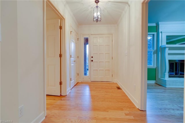 foyer with crown molding, a notable chandelier, and light wood-type flooring