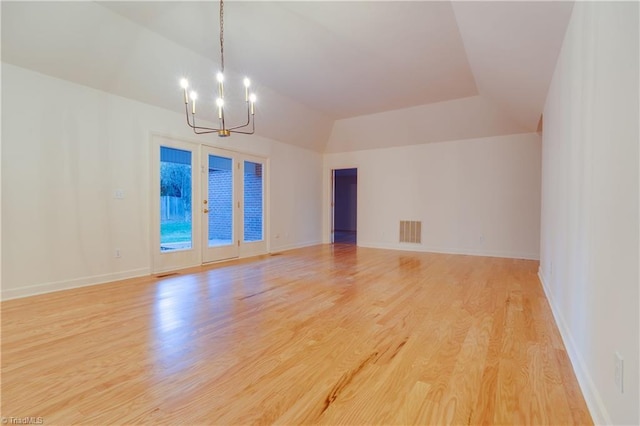 unfurnished room featuring a chandelier, light hardwood / wood-style floors, and lofted ceiling