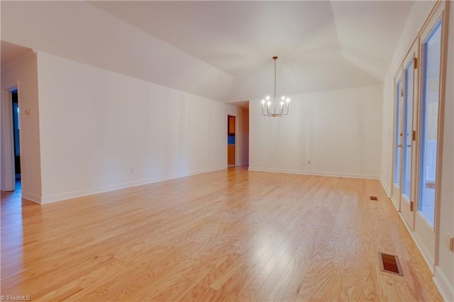 unfurnished room featuring an inviting chandelier, light hardwood / wood-style floors, and vaulted ceiling