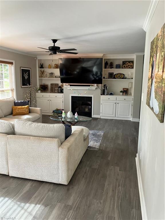 120 King Arthur Dr, King, NC 27021 - living area featuring crown molding, a ceiling fan, a glass covered fireplace, dark wood finished floors, and baseboards