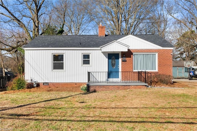 view of front of home featuring crawl space, a chimney, a front yard, and roof with shingles