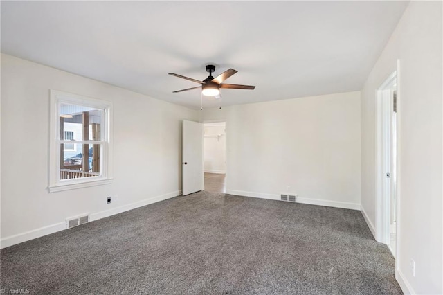 empty room with carpet, visible vents, and baseboards