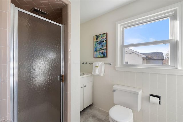 full bathroom featuring vanity, a shower stall, tile walls, toilet, and tile patterned floors