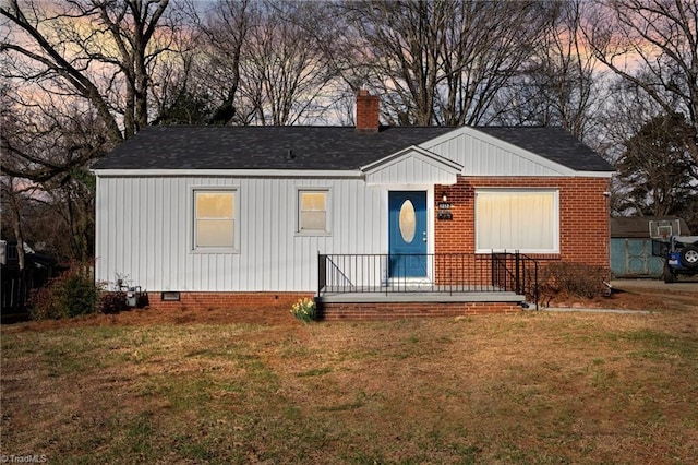 view of front of home with crawl space, a chimney, a front lawn, and a shingled roof