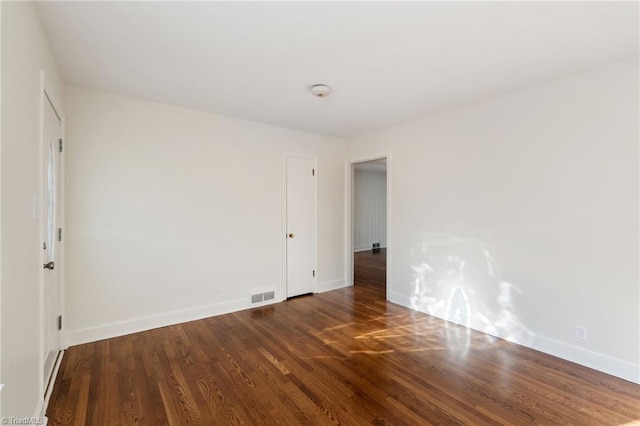 spare room with visible vents, baseboards, and wood finished floors