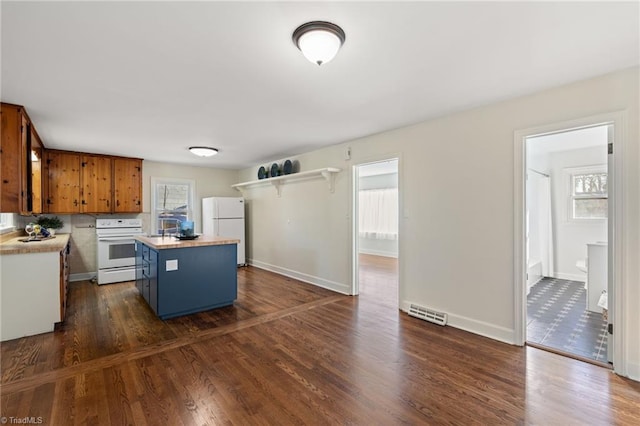 kitchen featuring a kitchen island, light countertops, brown cabinets, dark wood-style floors, and white appliances