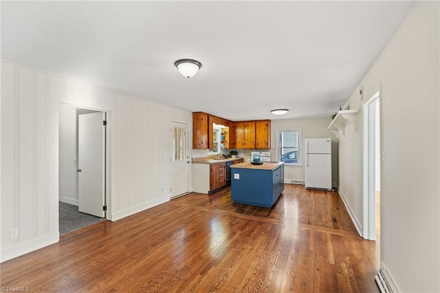 kitchen featuring a kitchen island, dark wood finished floors, light countertops, brown cabinets, and freestanding refrigerator