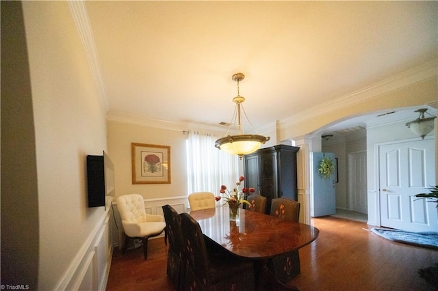 dining area with decorative columns, ornamental molding, and dark wood-type flooring