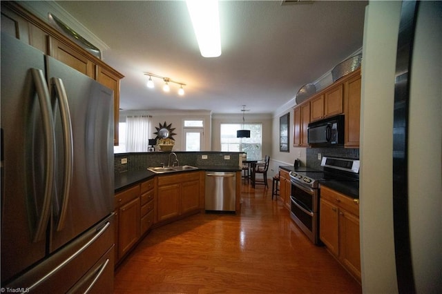 kitchen featuring appliances with stainless steel finishes, pendant lighting, tasteful backsplash, sink, and crown molding