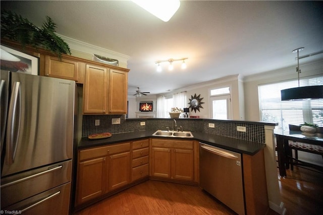 kitchen with appliances with stainless steel finishes, sink, decorative backsplash, kitchen peninsula, and crown molding