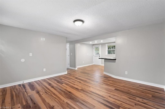 unfurnished living room with wood-type flooring and a textured ceiling