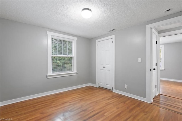 unfurnished bedroom featuring hardwood / wood-style floors, a textured ceiling, and a closet