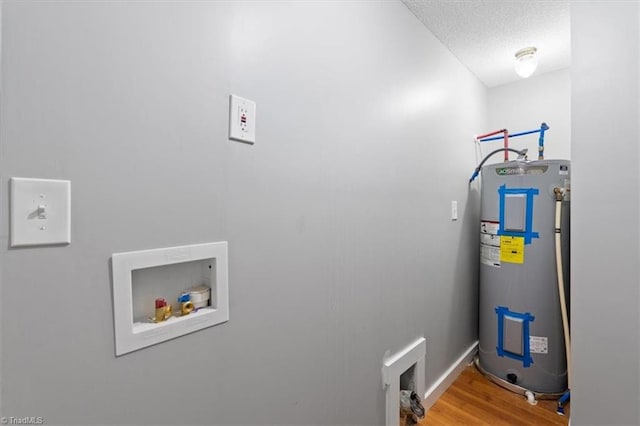 laundry room with electric water heater, hookup for a washing machine, a textured ceiling, and hardwood / wood-style floors