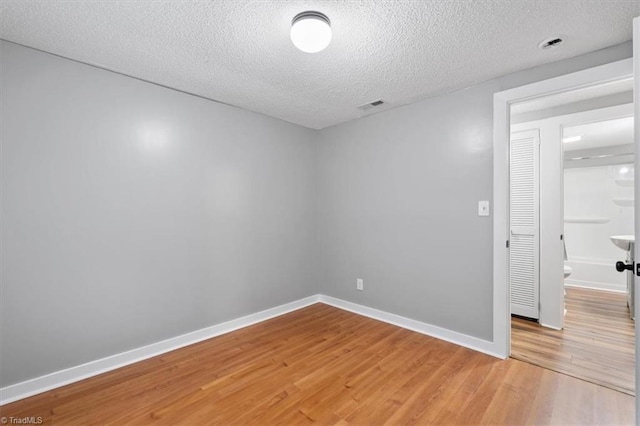 spare room featuring wood-type flooring and a textured ceiling