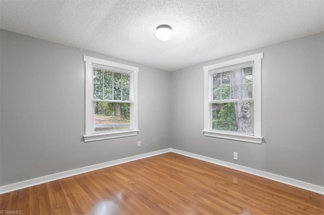 unfurnished room with a wealth of natural light, hardwood / wood-style floors, and a textured ceiling