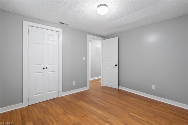 unfurnished bedroom featuring a closet, hardwood / wood-style floors, and a textured ceiling