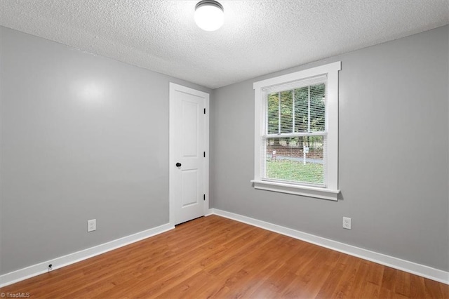 unfurnished room with hardwood / wood-style flooring and a textured ceiling