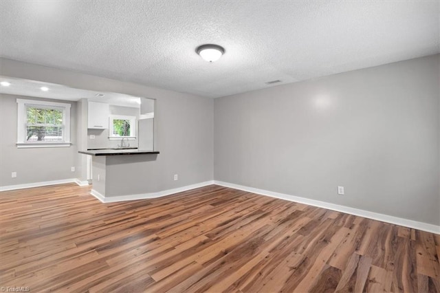 unfurnished living room with a textured ceiling and hardwood / wood-style flooring