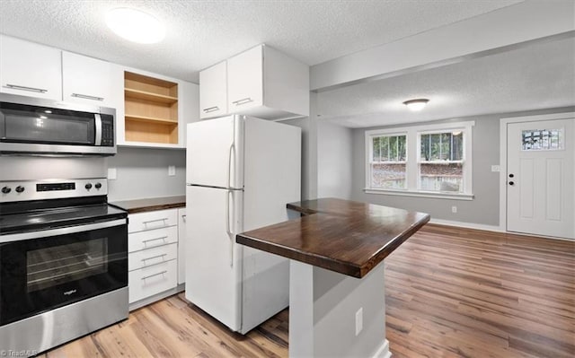 kitchen with stainless steel appliances, white cabinets, and light wood-type flooring