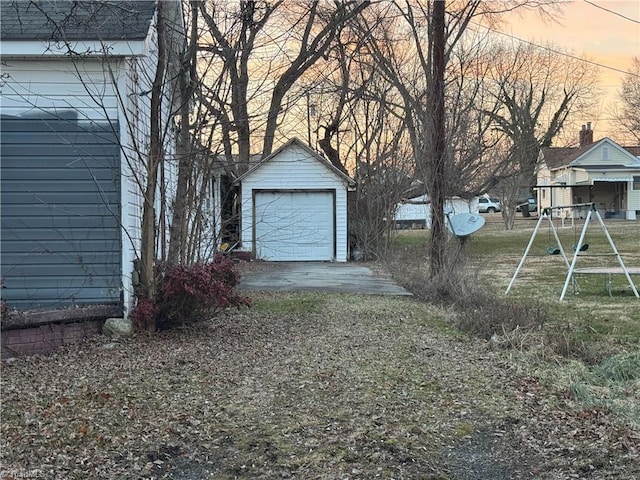 yard at dusk featuring a garage and an outbuilding