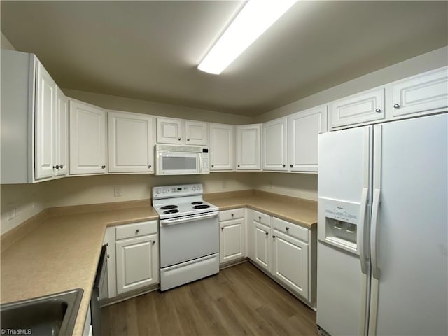 kitchen featuring white cabinetry, sink, white appliances, and hardwood / wood-style flooring