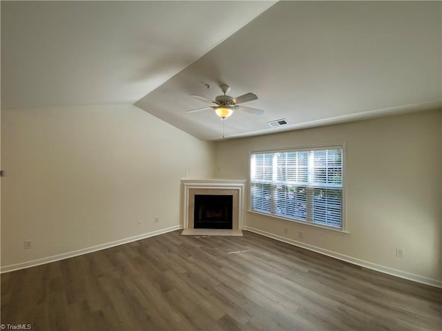 unfurnished living room with a tile fireplace, vaulted ceiling, dark wood-type flooring, and ceiling fan