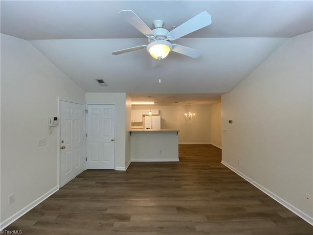 unfurnished living room featuring ceiling fan with notable chandelier, vaulted ceiling, and dark hardwood / wood-style floors