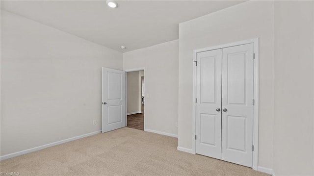 unfurnished bedroom with light carpet and a closet